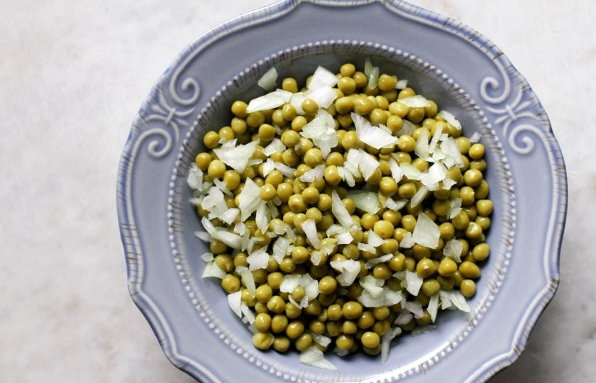 1. Этап. Салат с зелёным консервированным горошком: Откройте банку зелёного консервированного горошка и слейте сок. Выложите горошек в салатницу. Мелко порубите репчатый лук и добавьте к горошку.