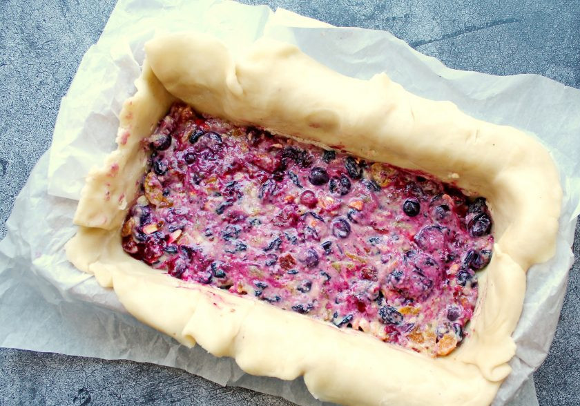 1. Этап. Шотландский новогодний кекс: Тесто раскатайте между двух пергаментов в тонкий пласт. Выложите тесто в форму 12 на 26 сантиметров застеленную пергаментом. Выложите внутрь теста начинку.