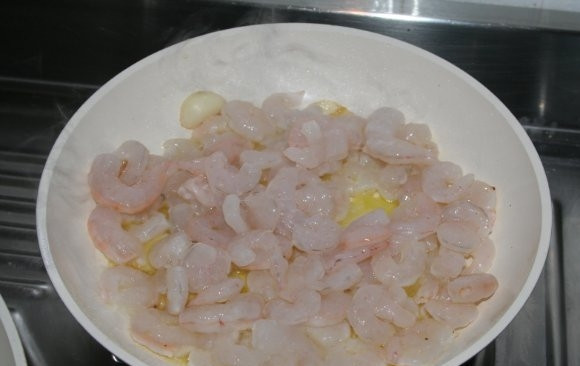 1. Этап. Блинчики с креветками: На отдельную сковородку добавьте немного растительного или оливкового масла, зубчик чеснока (он придаст креветкам очень приятный аромат) и высыпьте креветки. Постоянно помешивая, обжарьте их на среднем огне в течение 10 минут.