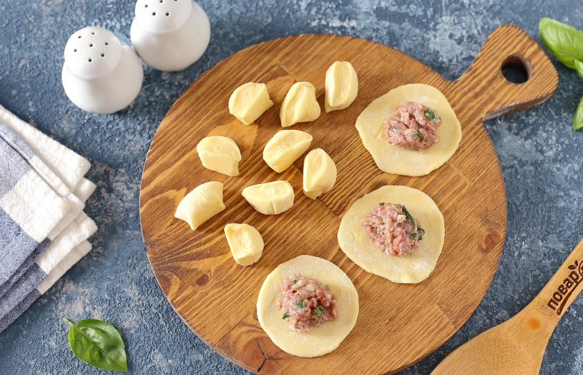 1. Этап. Пельмени с базиликом: От теста отрежьте кусок, раскатайте его колбаской и нарежьте кусочками. Размер зависит от желаемого размера пельменей. Затем каждый кусочек обваляйте с двух сторон в муке, раскатайте кружочком и выложите по центру начинку.