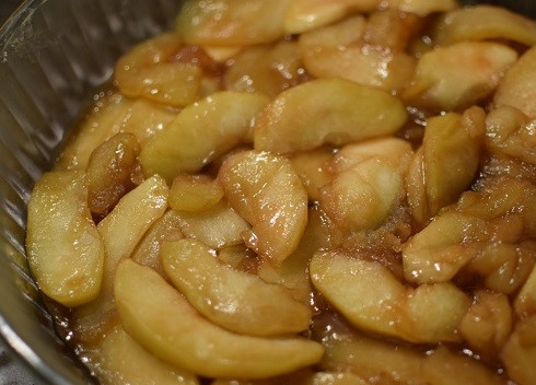 1. Этап. Карамельный яблочный пирог: Форму для пирога, диаметром в 24 см, смазываем маслом и выкладываем яблоки в карамели.