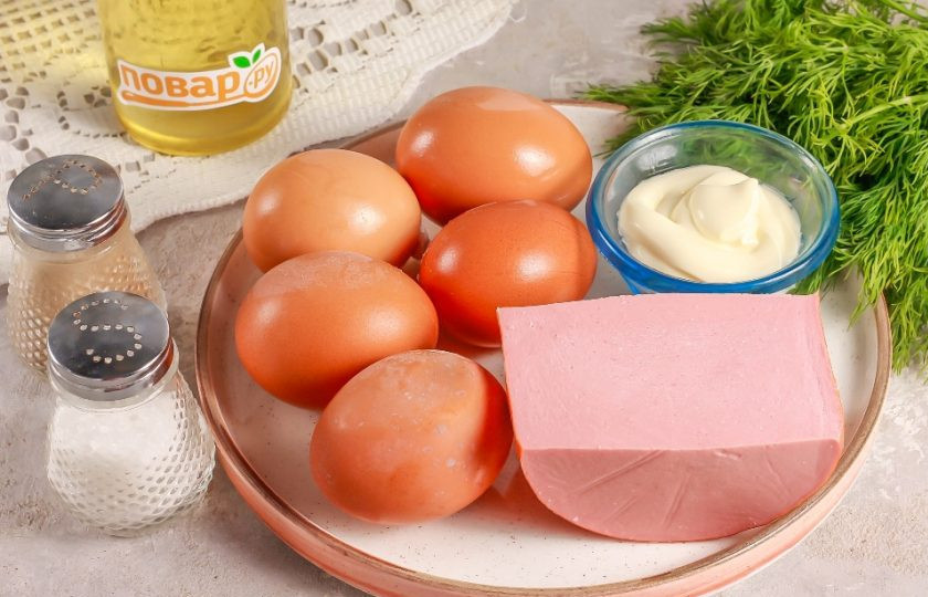 1. Этап. Яйца фаршированные вареной колбасой: Подготовьте указанные ингредиенты. Куриные яйца заранее отварите примерно 12-15 минут и затем остудите в ледяной воде еще 5-10 минут.