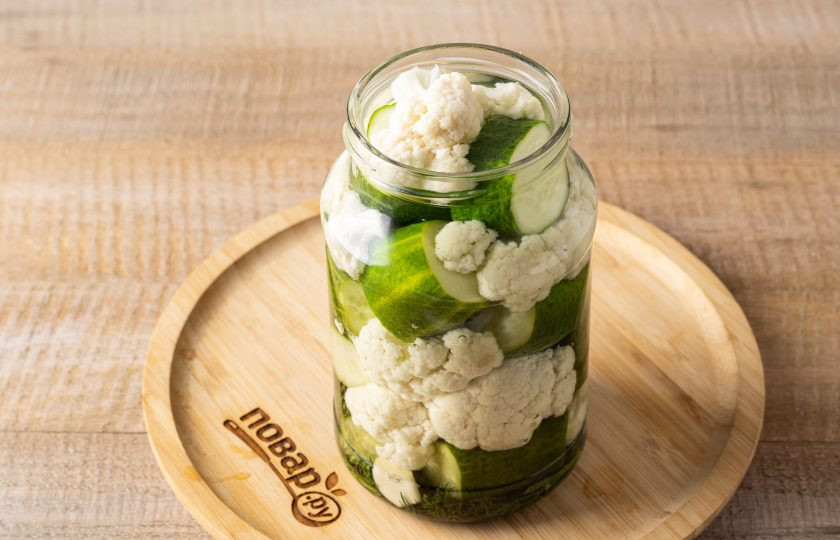 1. Этап. Цветная капуста маринованная с огурцами на зиму: Влейте горячую воду в банку. Прикройте крышкой и оставьте пропариться на 35 минут.