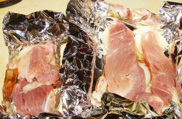 1. Этап. Кролик в фольге: Затем мы нарезаем фольгу на прямоугольники и заворачиваем их края. На дно кармашка кладем кольца лука, на них выкладываем замаринованное мясо, добавляем в каждый кармашек по пол чайной ложки жидкого дыма и посыпаем крольчатину молотым перцем.