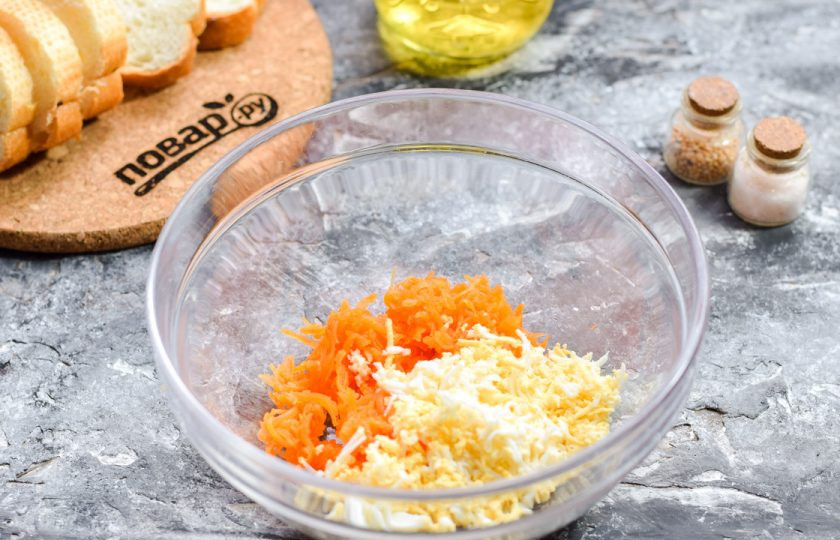 1. Этап. Запеченные бутерброды с рыбой: Вареную морковь и вареное куриное яйцо натрите на мелкой терке. Переложите ингредиенты в миску.