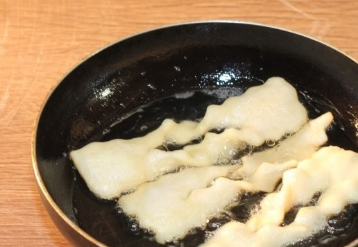 1. Этап. По мотивам кребли или вергуны: 14. Разогрейте растительное масло в подходящей для жарки посуде. Сделайте огонь средним и начните жарить заготовки, выкладывая их порциями по несколько штук. Они должны свободно плавать в масле, чтобы равномерно прожариться. Учитывайте, что выпечка увеличатся в размере.