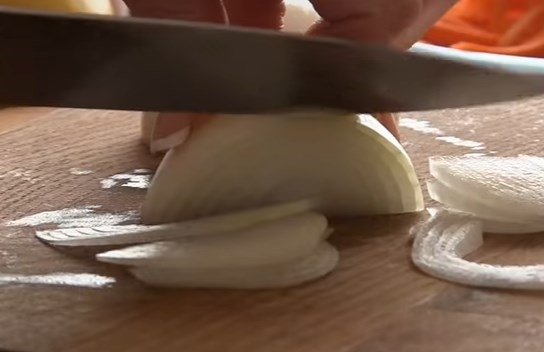 1. Этап. Острый овощной салат из дайкона: 4. Лук нарежьте полукольцами.