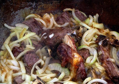 1. Этап. Шурпа из баранины в казане: Добавляем лук, продолжаем обжаривать, пока лук не станет золотистым.