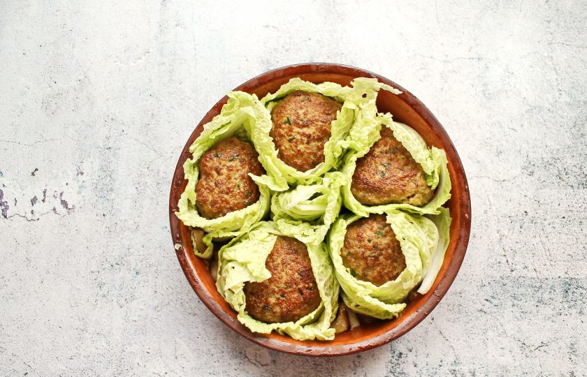 1. Этап. Тефтели Львиные головы: Каждый тефтель плотно обверните подготовленными листьями пекинской капусты и выложите в форму на грибной соус.