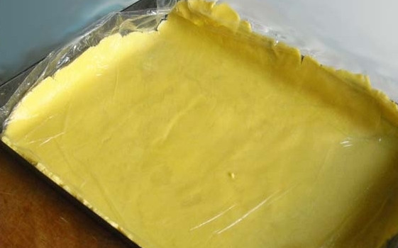 1. Этап. Тертый пирог с лимоном: 5. Накрутите тонко раскатанное тесто на скалку и перенесите его на противень. Сделайте небольшие бортики из теста.