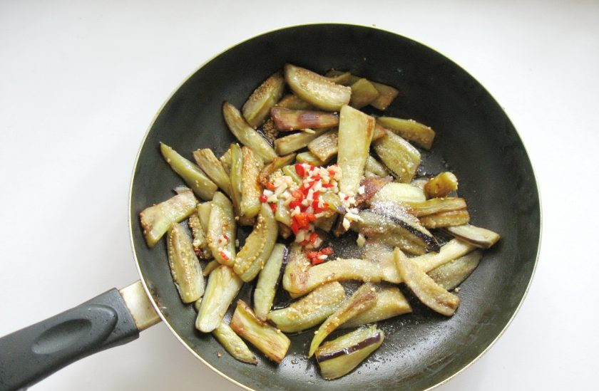 1. Этап. Острая закуска из баклажанов: Перец с чесноком добавьте в баклажаны. Всыпьте сахар.