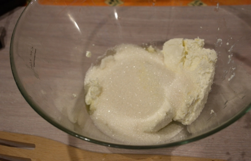 1. Этап. Творожная запеканка с песочным тестом: Добавьте сахар и два яйца. При помощи вилки смешайте компоненты в единую массу. Соединившись вместе (сахар и творог), творог пустит сыворотку и масса быстро станет жидкой. Это нам и нужно.