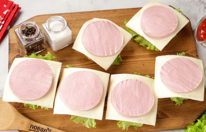 1. Этап. Праздничные бутерброды Змейка: Накройте помидоры ломтиком сыра и сверху выложите кружочек колбасы. Варёную колбасу можно заменить на копчёную или взять буженину, ветчину и даже домашние котлетки.