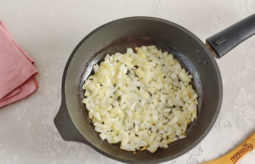 1. Этап. Белокочанная капуста в сыре в духовке: Лук нарежьте кубиками и обжарьте в сливочном масле до мягкости.