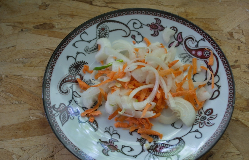 1. Этап. Драники в горшочках с мясом: Одну луковицу нарежьте полукольцами, а морковь натрите на терке. Обжарьте на масле морковь и лук одновременно до мягкости.