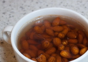 1. Этап. Конфеты с белым шоколадом: 1. Миндальные орешки положите в чашку и залейте крутым кипятком. По истечении 10 минут снимите с миндаля шкурку. Уложите его на противень и отправьте в духовку, чтоб орешки слегка поджарились при температуре 150 градусов. Периодически переворачивайте миндаль, чтоб не подгорал. Времени понадобится для этого приблизительно 25 минут.