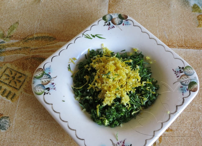 1. Этап. Фаршированный карп в фольге: Возьмите чистую тарелку. В нее положите вымытую и мелко нарубленную зелень. Добавьте к зелени немного натертой на мелкой терке цедры лимона.