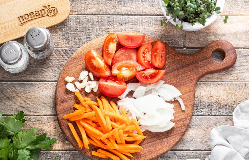 1. Этап. Грибной суп в банках на зиму: Пока варятся грибы, подготовьте овощи. Репчатый лук нарежьте полукольцами, помидоры крупными дольками, а морковь брусочками или натрите на крупной терке. Чеснок очистите и нарежьте пластинами.