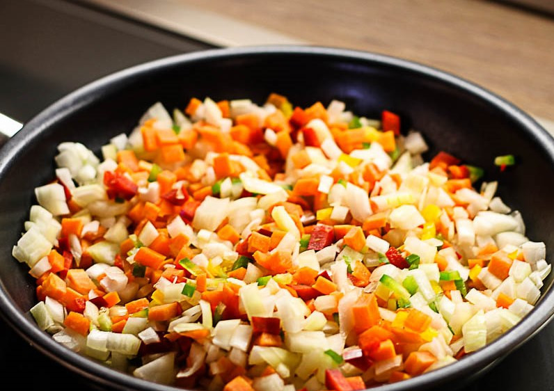 1. Этап. Прозрачный рыбный суп: На тефлоновой сковородке (без масла) обжариваем мелко порезанные кубиками лук, морковь и сладкий перец. Обжариваем все на среднем огне, постоянно перемешивая, около 10 минут.