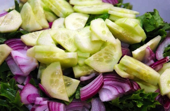 1. Этап. Вкусный салат из кальмара: Салатные листья хорошо вымойте и просушите. Нарвите салат руками крупными кусочками и выложите на тарелку. Очистите огурец и нарежьте его дольками. А красный лук — полукольцами или четверьтькольцами. Выложите огурец и лук на салатные листья.