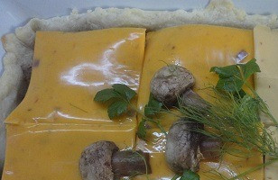 1. Этап. Пирог с грибами и сыром: Дно формы с тестом выложить пластинками сыра, а на него начинку. Сверху накрыть оставшимися пластинками сыра и украсить грибами (по желанию).