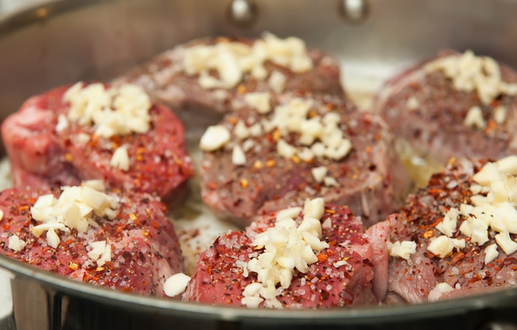 1. Этап. Жареное мясо с чесноком: Мясо опустить в разогретое масло, посолить, поперчить и посыпать мелким чесноком.