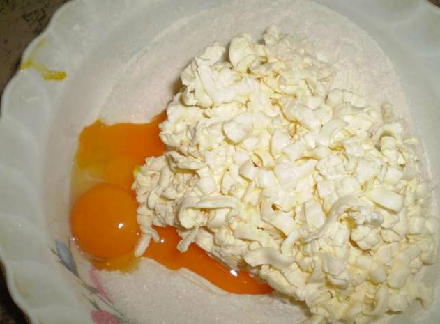 1. Этап. Корзиночки с вишней: Замешиваем тесто для наших корзиночек. Просеиваем муку с разрыхлителем. Вбиваем яйца. Берите 2 яйца, если маленькие, и одно, если большое. Насыпаем половину порции сахара. Кладем щепотку соли и размягченное сливочное масло. Замешиваем масляное тесто и скатываем его в колобок. Накрываем пищевой пленкой и отставляем на полчасика.