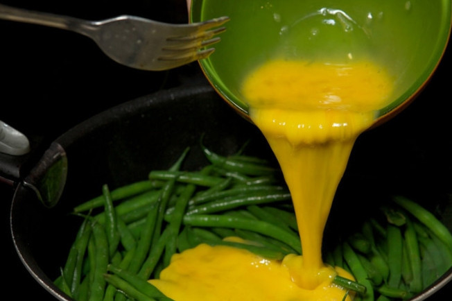 1. Этап. Зеленая фасоль с яйцом: 5. Влейте к фасоли куриные яйца и перемешайте сразу.