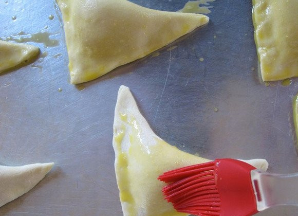 1. Этап. Слойки из бездрожжевого теста с сыром: 7. Смажьте с помощью кисточки взбитым желтком.