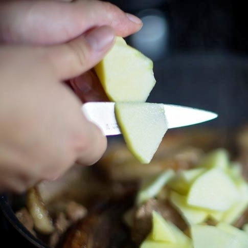 1. Этап. Тушеное мясо утки с яблоками: Тонкими дольками нарезаем яблоко в сковороду.