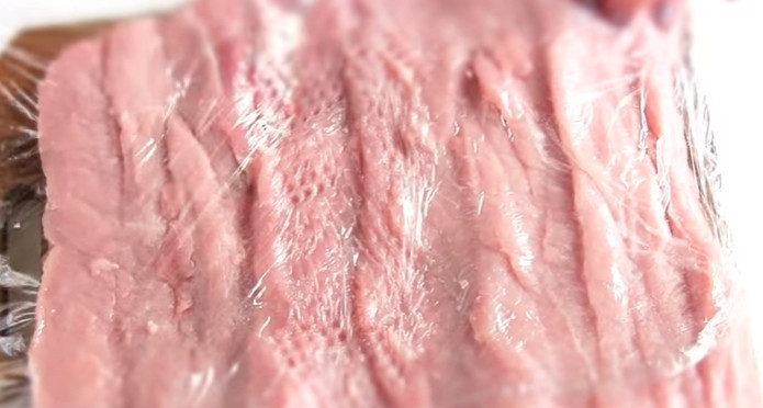 1. Этап. Мясной рулет с клюквой: 2. Накройте мясо пищевой пленкой и отбейте молотком. Затем посолите и поперчите.