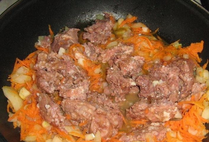 1. Этап. Картошка с тушенкой: Далее выложим на сковородку тушенку, разровняем ее по всей сковородке и добавим нарезанный картофель.