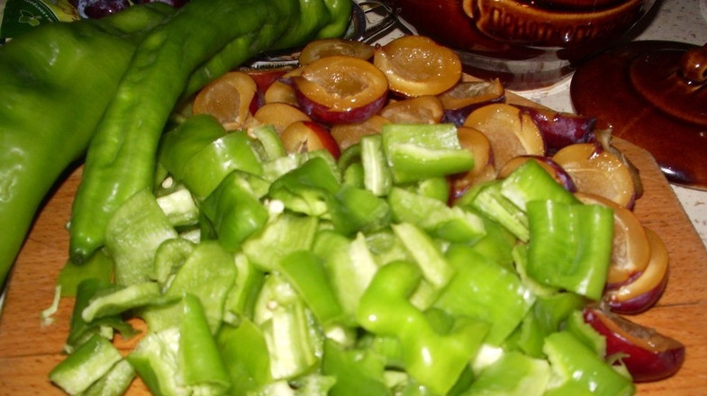 1. Этап. Свинина со сливой в духовке: Вымойте под проточной водой сливы и перец, обсушите их бумажными полотенцами. Фрукты разрежьте на две половинки, удалите косточки. Перец разрежьте, очистите от семян и нарубите ножом на небольшие кусочки.