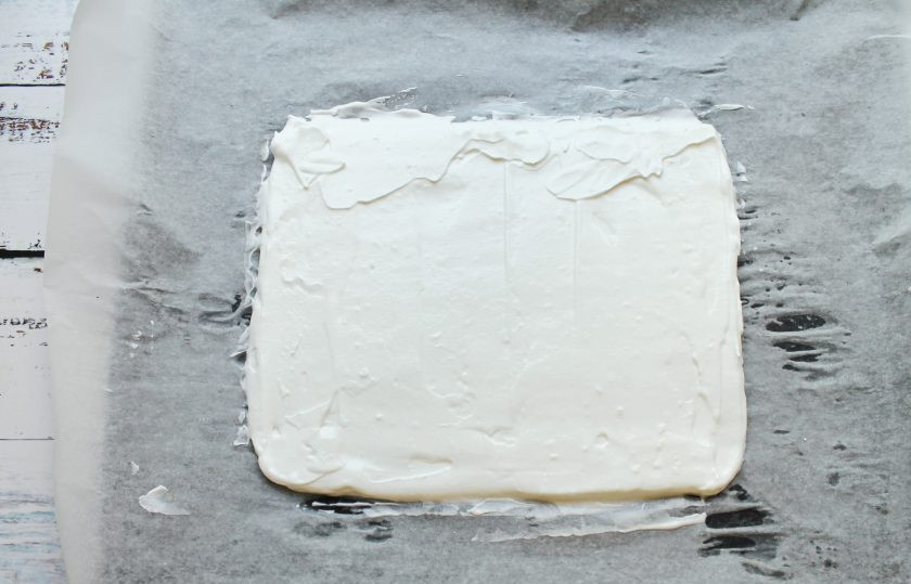 1. Этап. Меренговый рулет с творожным кремом: Противень застелите пергаментом и выложите меренговое тесто. Разровняйте в прямоугольник 35 на 35 сантиметров.