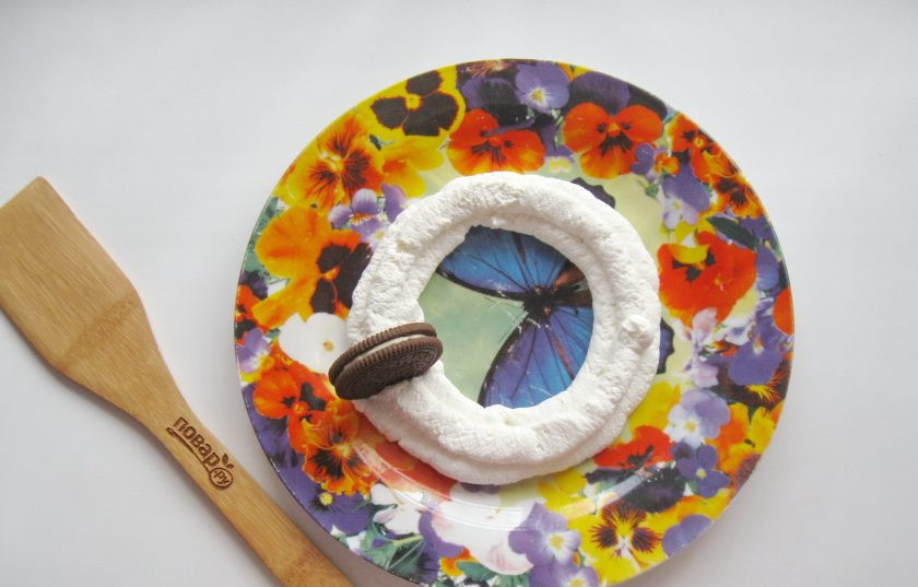 1. Этап. Десерт Новогодний венок: С помощью кондитерского мешка выложите круг из творога на блюдо. После вставьте в творог по кругу шоколадное печенье.