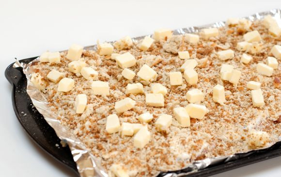 1. Этап. Куриная грудка в сметане: 5. Сверху присыпать измельченными панировочными сухарями, а чтобы получилась вкусная корочка сверху выложить небольшие кусочки сливочного масла. Для аппетитной корочки можно использовать также тертый сыр, например.