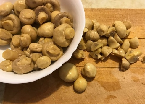 1. Этап. Оливье по-мексикански: 3. Пока варятся яйца и морковь, нарезаем другие ингредиенты. Маринованные шампиньоны, если они небольшие, достаточно разрезать на 4 части.