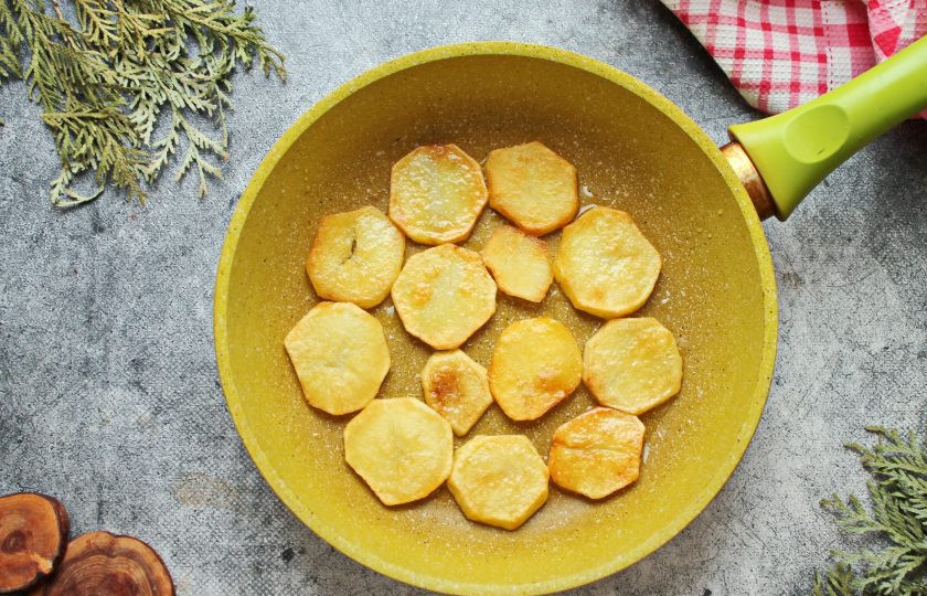 1. Этап. Грибы по-деревенски: Картофель почистите, сполосните и отварите до готовности на среднем огне в соленой воде. Слейте отвар и полностью остудите картошку. Остывший картофель порежьте кружочками и обжарьте с двух сторон на растительном масле. Выложите обжаренный картофель в форму для запекания.