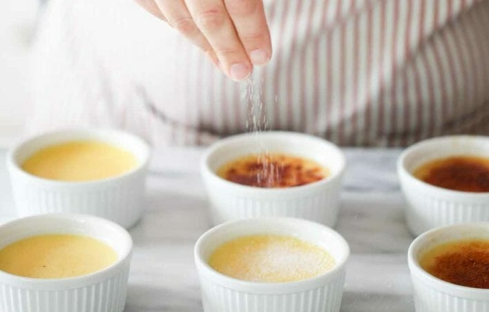 1. Этап. Классический десерт Крем-брюле: 10. Остудите крем-брюле в холодной воде в течение 15 минут. Посыпьте каждую форму оставшимся сахаром.