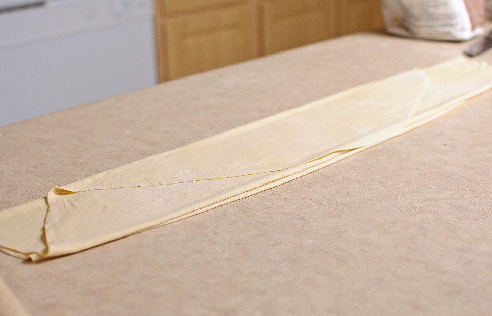 1. Этап. Манты: Раскатать тесто. Присыпать мукой, чтобы избежать слипания. Сложить в длинную широкую полоску.