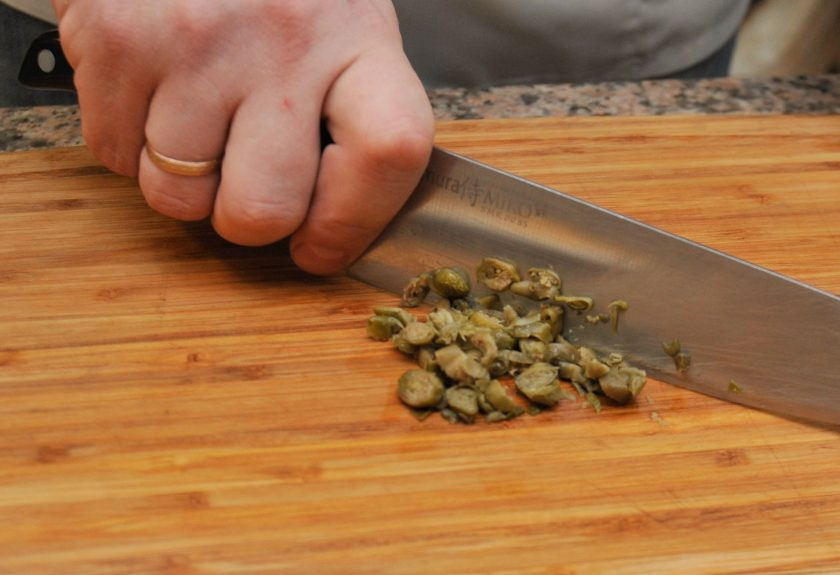 1. Этап. Салат с отварным языком: 3. Изюминка этого салата — каперсы. Именно они придадут удивительный вкус нашему мясному салату. Нарезаем каперсы так же мелко, как и остальные ингредиенты.