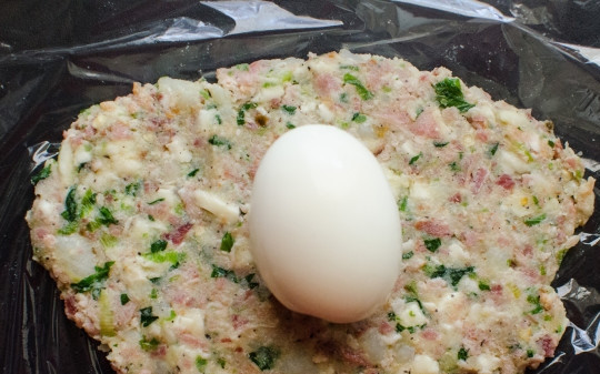 1. Этап. Яйца шотландские: 3. На кусочек пищевой пленки выложите 1/5 фарша. В центр - яйцо. Аккуратно соедините края пленки, формируя шарик.