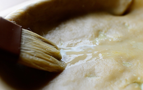 1. Этап. Пирог в горшочке с курицей и овощами: 6. Смешайте яйцо и воду, смажьте этой смесью тесто. Выложите равномерно начинку по периметру коржа.