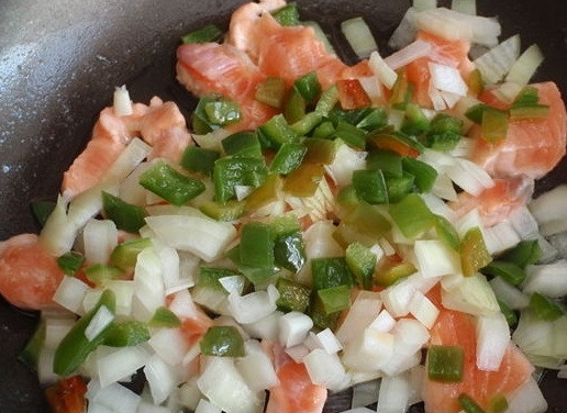 1. Этап. Омлет с лососем: 4. Нарежьте филе небольшими кубиками. Очистите и промойте болгарский перец, очистите луковицу. Перец и лук нарежьте кубиками. В сковороде на среднем огне нагрейте масло и обжарьте, помешивая, лосось, перец и лук.