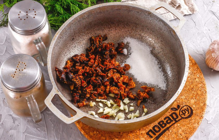 1. Этап. Инжирная горчица: Нарежьте вяленый инжир мелкими кубиками, срезая хвостики. Очистите 1-2 зубчика чеснока, промойте их в воде и измельчите, добавьте в казан вместе с сахаром, нарезкой инжира, солью и молотым черным перцем.