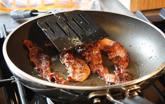 1. Этап. Шампиньоны, фаршированные беконом и сыром: 1. На сухую сковороду выложите бекон, обжарьте его до румяности. Снимите после с огня и выложите на бумажное полотенце. На сковороду же отправьте измельченный лук. Обжарьте его до золотистого цвета.