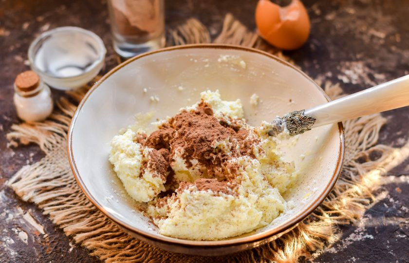 1. Этап. Варшавский сырник: Разделите тесто на две части, в одну часть добавьте какао-порошок и хорошо перемешайте.