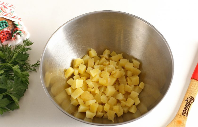 1. Этап. Салат Новогодняя сказка: Картофель очистите, нарежьте мелкими кубиками и сложите в глубокую миску.