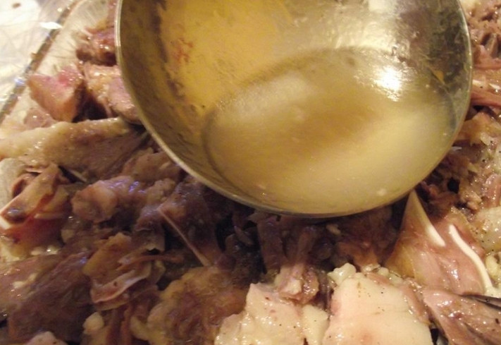 1. Этап. Холодец из свиной рульки: Раскладываем мясо в форму и заливаем бульоном.