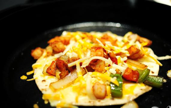 1. Этап. Кесадилья с креветками: 4. В отдельной сковороде нагреть масло. Выложить в сковородке, затем слой тертого сыра, овощи и креветки. Посыпать еще небольшим количеством сыра сверху и накрыть второй лепешкой. Жарить на обеих сторонах, добавляя масло перед переворачиванием, так как лепешки не должны быть сухими.